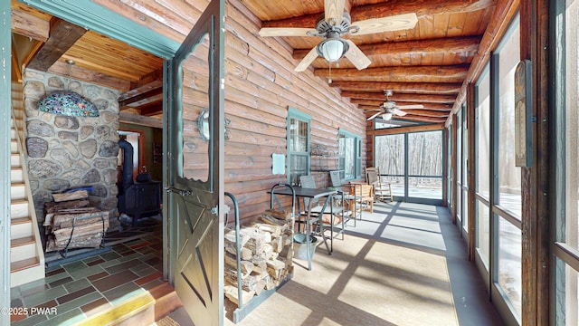 sunroom / solarium featuring beamed ceiling, ceiling fan, and wooden ceiling