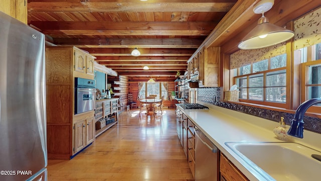 kitchen with sink, log walls, a wealth of natural light, and stainless steel appliances