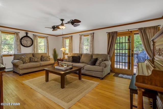 living room with a baseboard heating unit, ornamental molding, ceiling fan, and light wood-type flooring