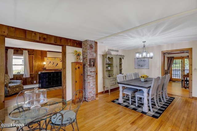 dining room with a notable chandelier, light hardwood / wood-style floors, a wall unit AC, and a wealth of natural light