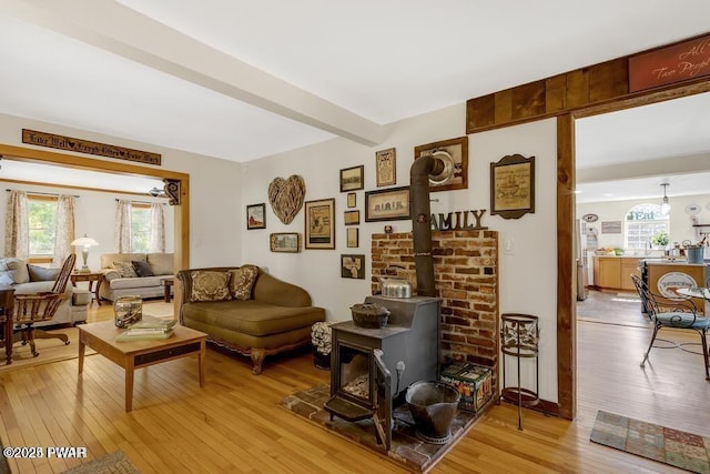 sitting room featuring beamed ceiling, light hardwood / wood-style floors, and a wood stove