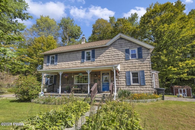 front facade with a porch, a storage shed, and a front lawn