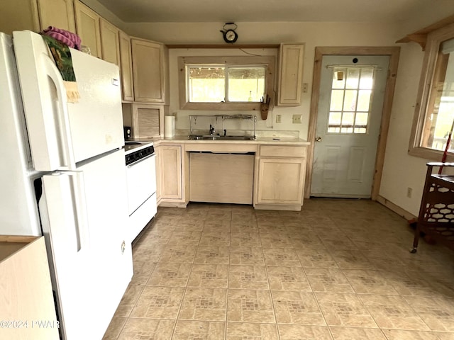 kitchen featuring light brown cabinetry, sink, and white appliances