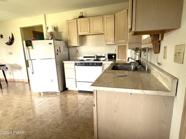 kitchen with light brown cabinets, white appliances, and sink