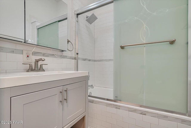 bathroom with tiled shower / bath, vanity, and decorative backsplash