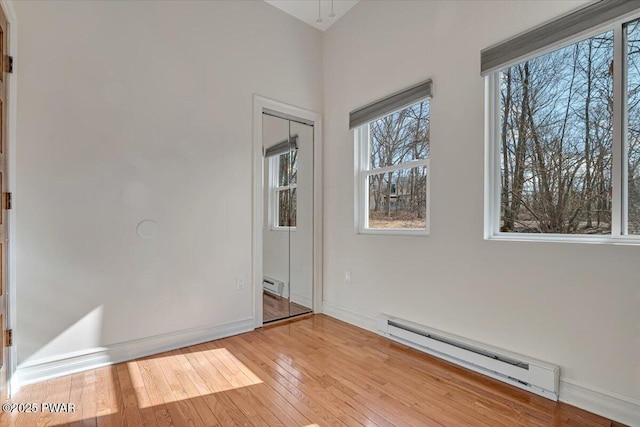 spare room with baseboards, a baseboard heating unit, and light wood-style floors