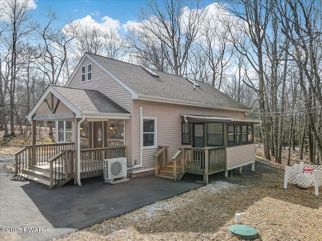 view of front of house featuring roof with shingles, ac unit, a deck, a sunroom, and a patio