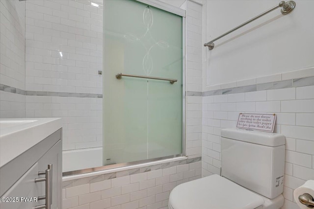 bathroom featuring toilet, tile walls, vanity, and shower / bathing tub combination