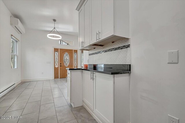 kitchen with an AC wall unit, dark countertops, tasteful backsplash, white cabinets, and light tile patterned flooring