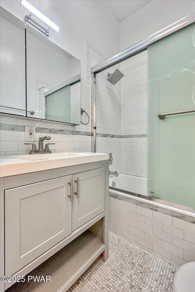 bathroom featuring vanity, tile patterned flooring, tiled shower / bath combo, tile walls, and tasteful backsplash