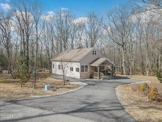 view of front of house with covered porch, driveway, and a shingled roof