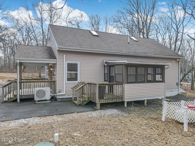 rear view of house featuring ac unit, a wooden deck, and roof with shingles