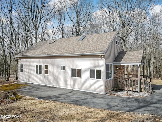 view of property exterior with driveway and a shingled roof