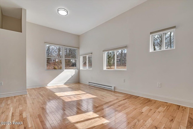 unfurnished room featuring baseboard heating, baseboards, and light wood-style floors