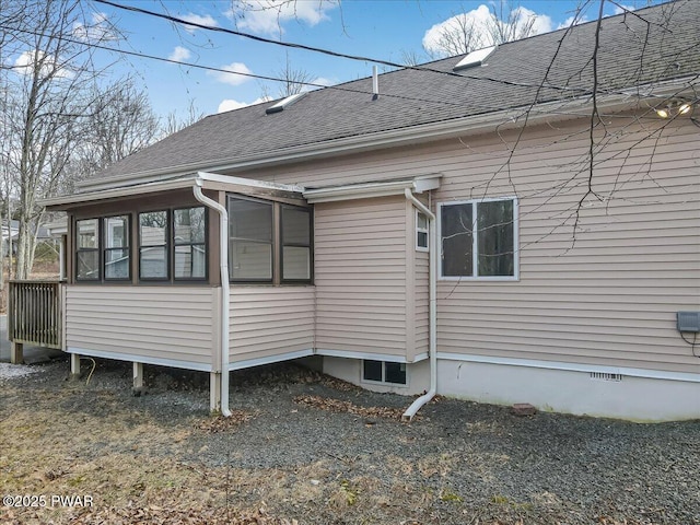 view of home's exterior with crawl space, a shingled roof, and a sunroom