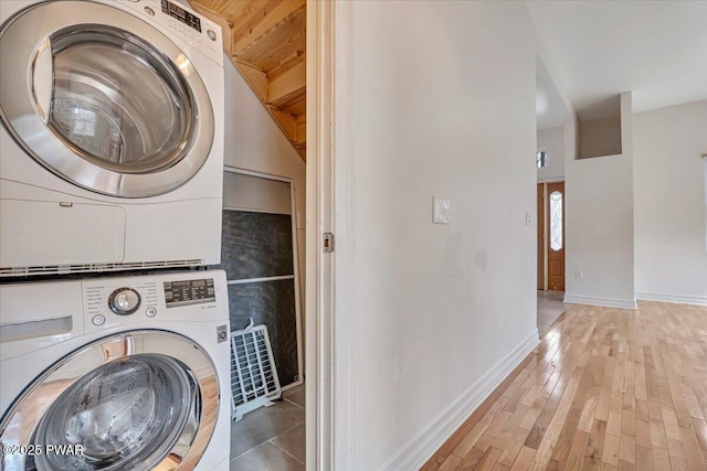 washroom featuring laundry area, wood finished floors, stacked washer and clothes dryer, and baseboards