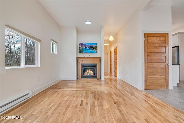 unfurnished living room with a lit fireplace, baseboards, a baseboard heating unit, and light wood-style floors