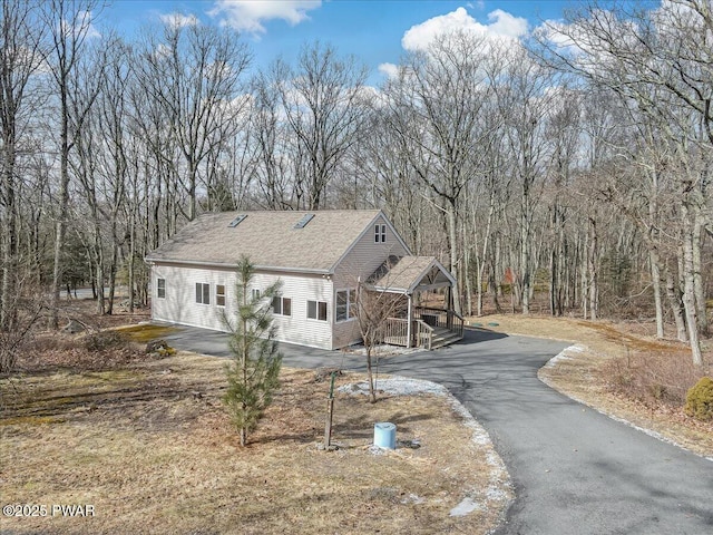 view of front of property featuring driveway and roof with shingles