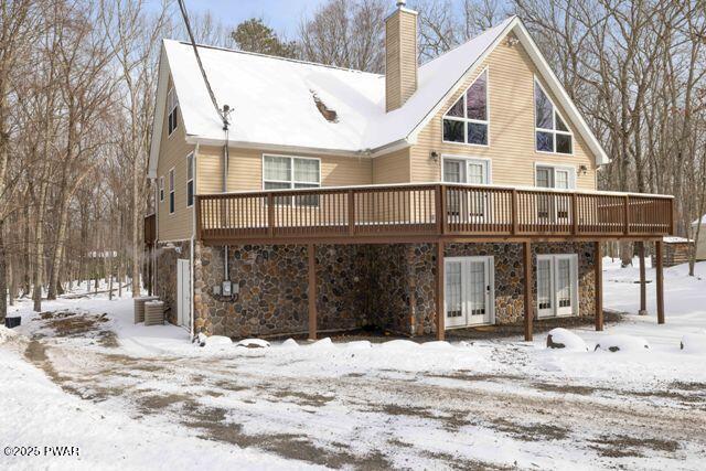 snow covered back of property featuring a wooden deck