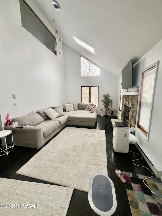 living room featuring dark wood-type flooring, a skylight, a fireplace, and high vaulted ceiling