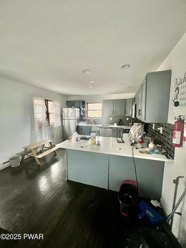 kitchen with a healthy amount of sunlight, kitchen peninsula, appliances with stainless steel finishes, and gray cabinetry