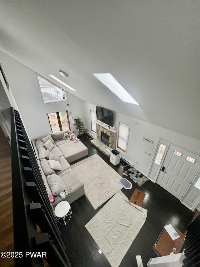 living room featuring vaulted ceiling with skylight and a fireplace