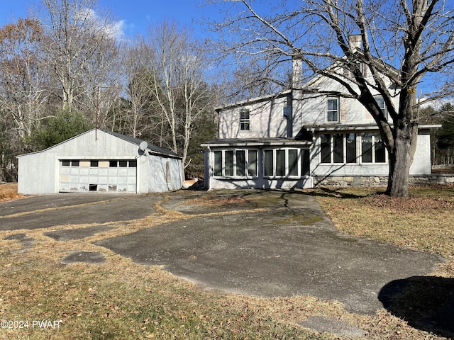 view of front of house featuring an outbuilding, a garage, and a sunroom