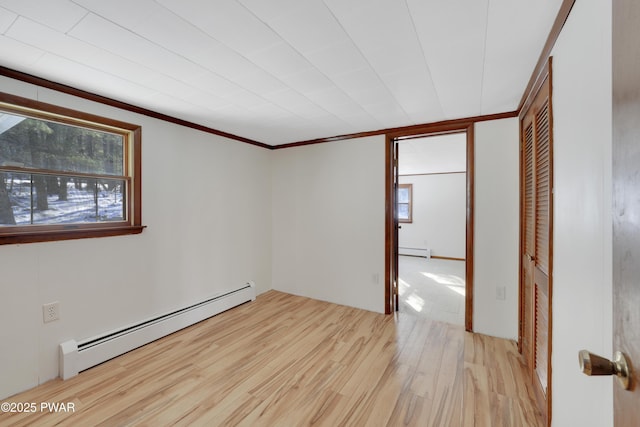 unfurnished room featuring a wealth of natural light, light hardwood / wood-style flooring, and a baseboard heating unit