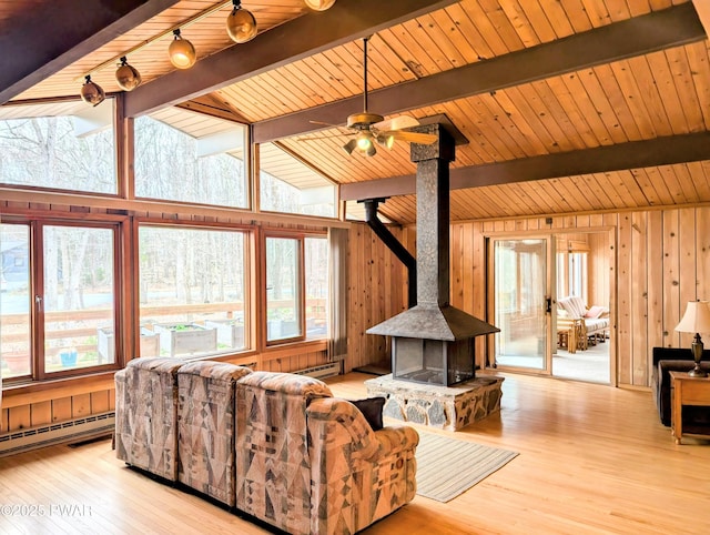 130 Willow Dr, Lords Valley, PA 18428 - living area with a wood stove, wood walls, a baseboard heating unit, and a wealth of natural light