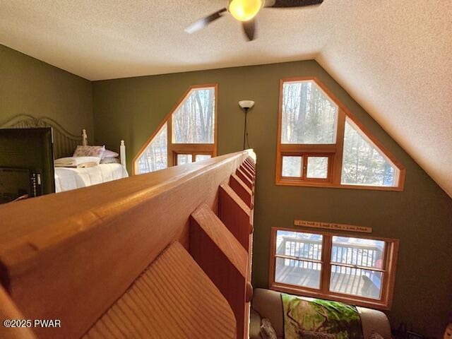 interior space featuring lofted ceiling, ceiling fan, and a textured ceiling