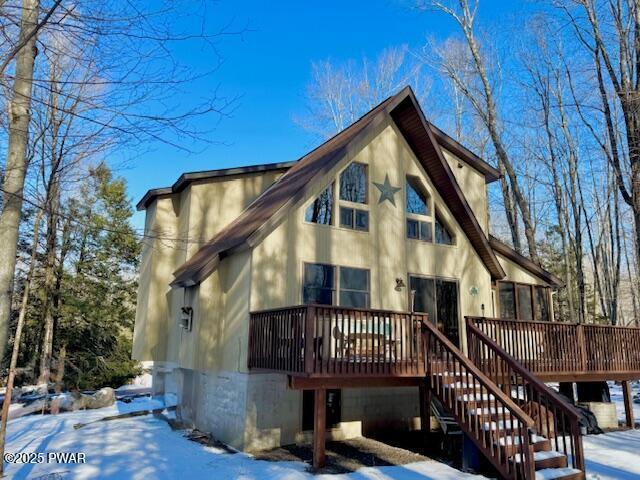 snow covered rear of property with a deck