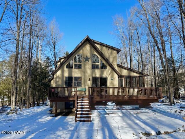 snow covered house featuring a deck