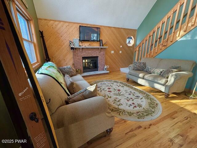 living room with hardwood / wood-style floors, a brick fireplace, and wood walls