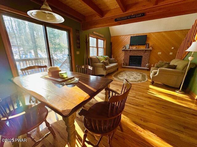 dining room featuring beamed ceiling, a fireplace, and hardwood / wood-style floors