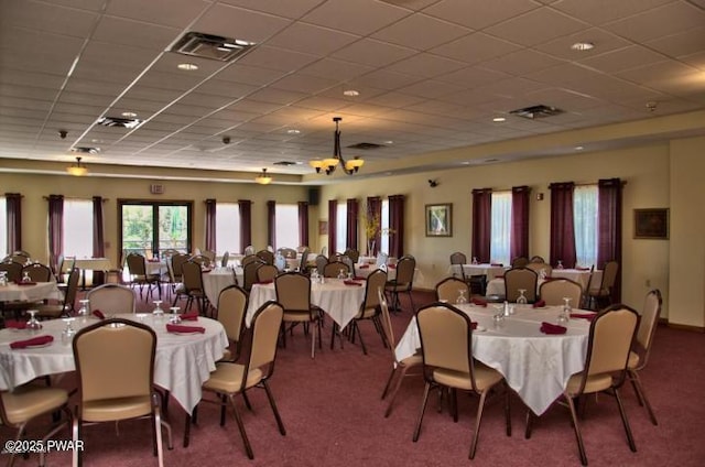 carpeted dining space featuring a paneled ceiling and a chandelier