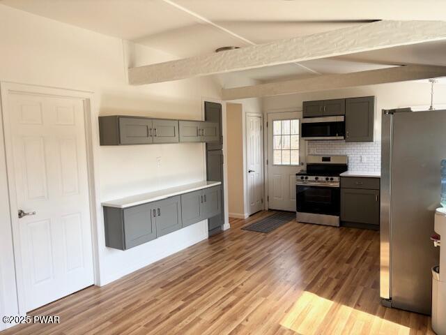 133 Arrowood Dr, Dingmans Ferry, PA 18328 - kitchen with appliances with stainless steel finishes, beam ceiling, gray cabinetry, wood finished floors, and backsplash