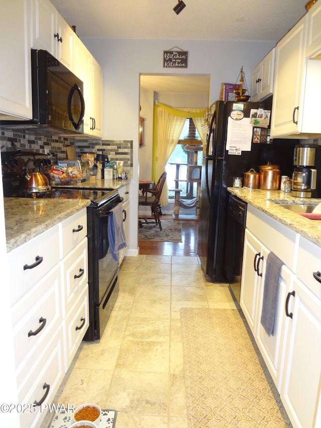 kitchen featuring light stone countertops, backsplash, white cabinets, and black appliances