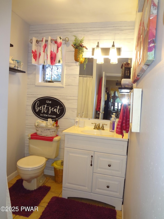 bathroom with toilet, tile patterned flooring, wood walls, and vanity