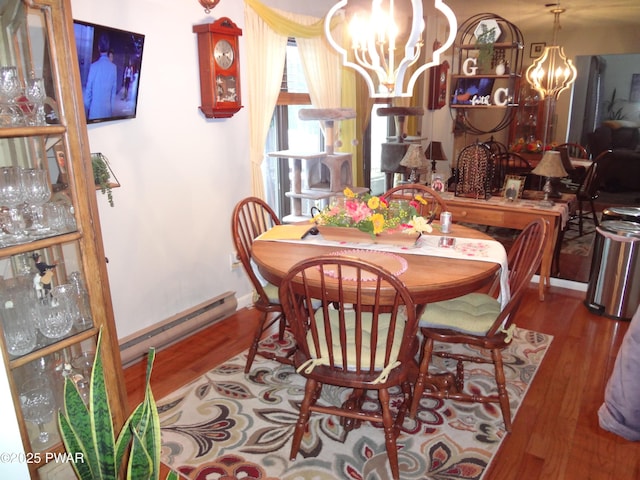 dining area with a baseboard radiator, wood-type flooring, and a notable chandelier