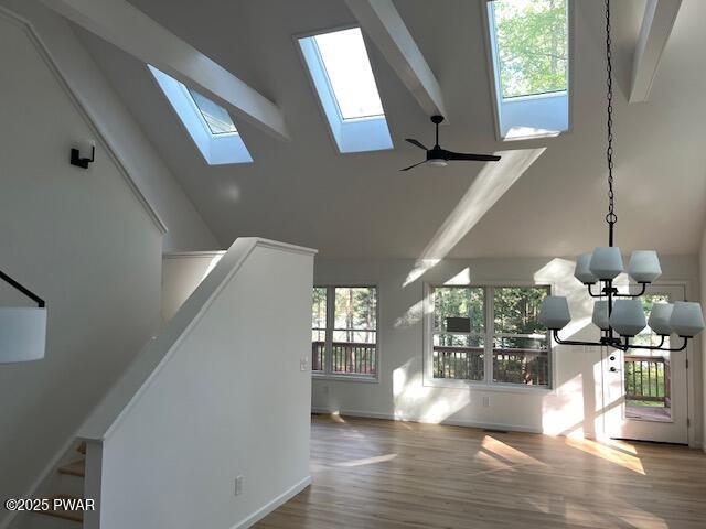 104 Maple Park Dr, Shohola, PA 18458 - unfurnished living room with high vaulted ceiling, a skylight, wood finished floors, and a chandelier