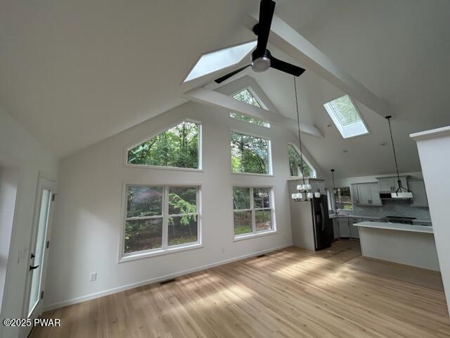 104 Maple Park Dr, Shohola, PA 18458 - unfurnished living room featuring a skylight, high vaulted ceiling, ceiling fan, light wood-style floors, and healthy amount of natural light