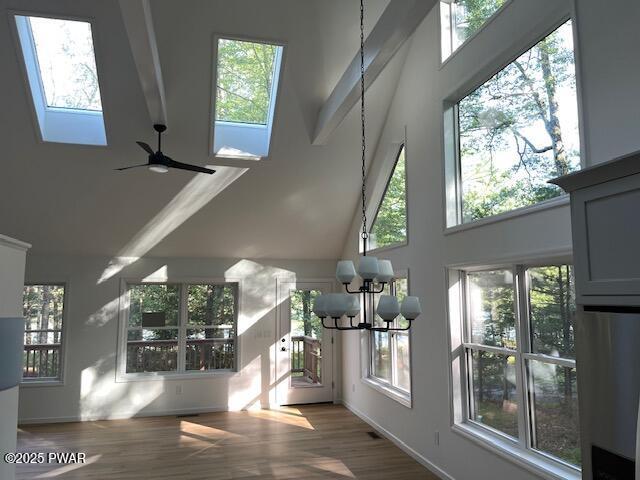 104 Maple Park Dr, Shohola, PA 18458 - unfurnished living room featuring a towering ceiling, a chandelier, a skylight, wood finished floors, and plenty of natural light