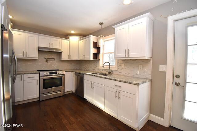 kitchen featuring pendant lighting, dark hardwood / wood-style floors, light stone countertops, white cabinetry, and stainless steel appliances