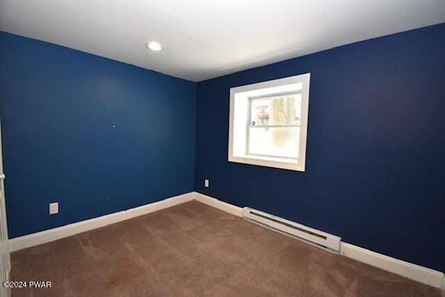 spare room featuring carpet floors and a baseboard heating unit