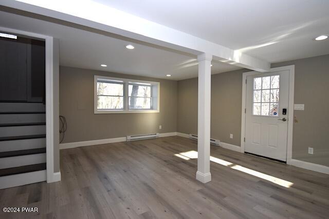 basement with baseboard heating, hardwood / wood-style floors, and a healthy amount of sunlight