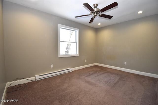 carpeted spare room featuring ceiling fan and a baseboard heating unit