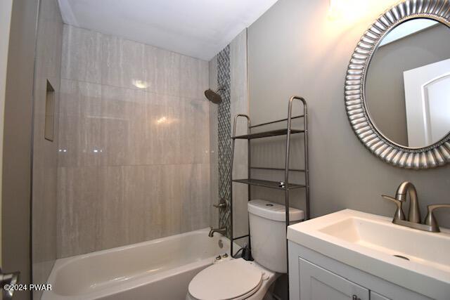 full bathroom with toilet, vanity, and tiled shower / bath