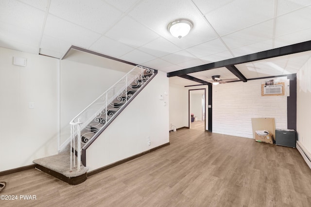 basement with hardwood / wood-style floors, a drop ceiling, ceiling fan, and a wall mounted AC