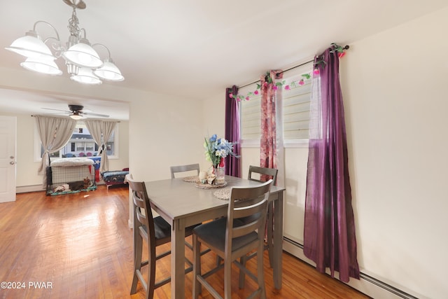 dining room with wood-type flooring, ceiling fan with notable chandelier, and a baseboard heating unit