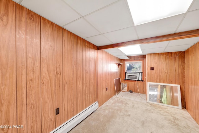 basement with a paneled ceiling, carpet flooring, and wooden walls